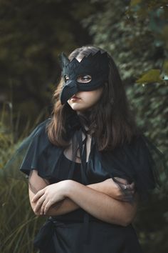 a woman wearing a mask and black dress