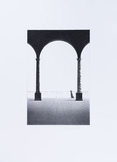 a black and white photo of a person sitting under an arch