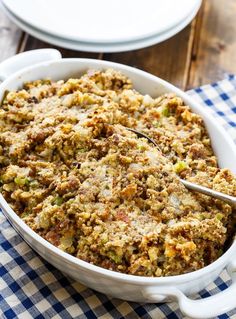 a casserole dish filled with stuffing on top of a blue and white checkered table cloth