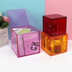 three boxes with different types of skin care products in them on a white table next to a pink and blue wall