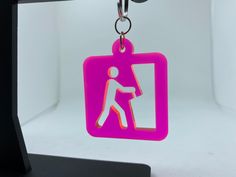 a pink keychain hanging from a hook with a person walking on the door