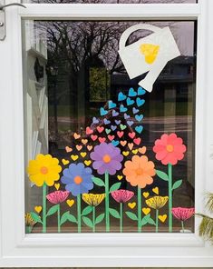 a window decorated with flowers, butterflies and a watering can in the center is a paper cutout