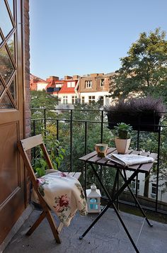 a balcony with a table and chair on it, looking out onto the city below