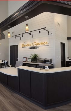 an empty reception area with black and white counter tops, wood flooring and lights