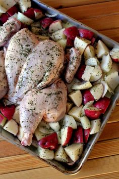 chicken, potatoes and carrots in a pan on a wooden table