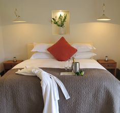 a bed with white linens and red pillows