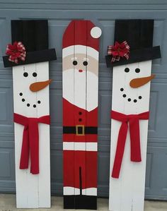 two snowmen made out of wooden planks with red bows