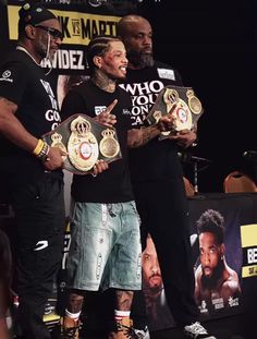 two men standing next to each other holding up their belts