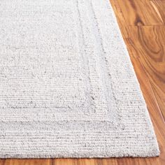 a white rug is on the floor with wooden floors and wood planks in the background