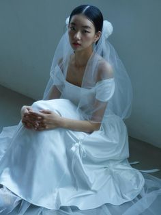 a woman in a white wedding dress sitting on the floor wearing a veil and shoes