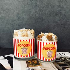 two jars filled with popcorn sitting on top of a table