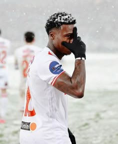 a soccer player wiping his face in the rain