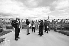 black and white photograph of people standing on top of a bridge looking at their cell phones