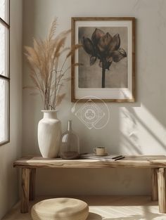 a white vase sitting on top of a wooden table next to a framed flower arrangement