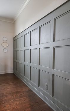 an empty room with wood floors and gray garage doors on the side of the wall