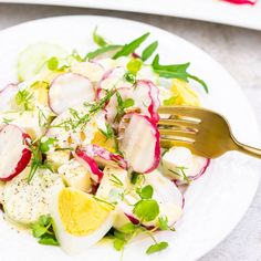 a salad with radishes, cucumbers and lemon on a white plate