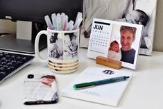 a desk with a laptop, coffee mug and calendar on it next to a keyboard