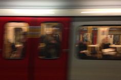 blurry image of people sitting on the seats of a subway train as it passes by