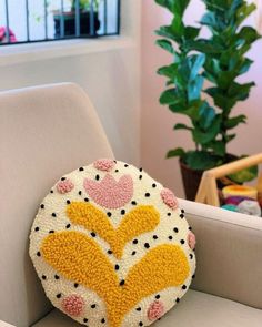 a decorative pillow sitting on top of a white chair next to a potted plant