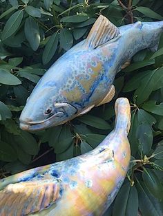 two ceramic fish sitting on top of green leaves