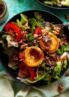 a salad with meat, tomatoes and lettuce in a bowl on a table