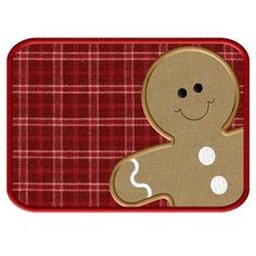 a gingerbread cookie on a red and white checkered mat with a smiling face