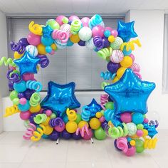 an arch made out of balloons and stars is displayed in front of a white wall