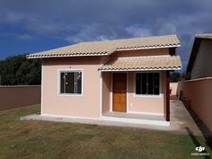 a small pink house sitting on top of a lush green field