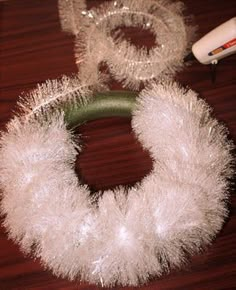 a white wreath sitting on top of a wooden table next to a hair dryer