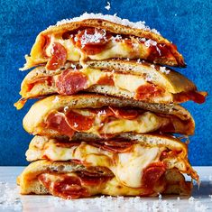 a stack of pizzas sitting on top of a table covered in cheese and pepperoni