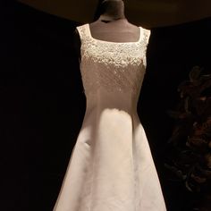 a white wedding dress on display in front of a black background