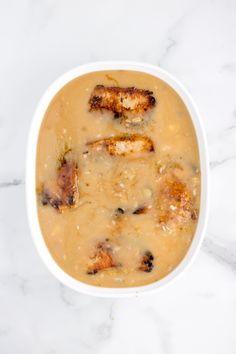 a white bowl filled with soup on top of a marble counter