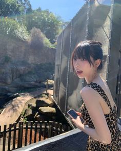 a woman in a leopard print dress holding a cell phone and looking at the camera