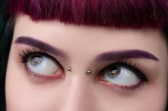 a woman with purple hair and piercing on her nose