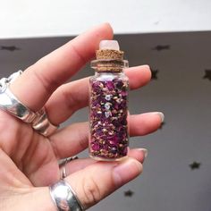 a person is holding a tiny bottle with flowers in it