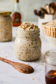 a jar filled with oatmeal sitting on top of a table next to a spoon