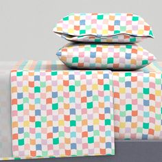 three pillows stacked on top of each other with different colored squares printed on them,