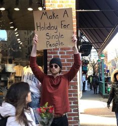 a man holding up a sign that says make a holiday for single people