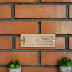 a brick wall with two planters and a sign on it that says meeting in progress