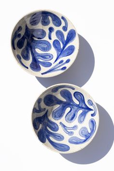 two blue and white bowls sitting next to each other on top of a white surface