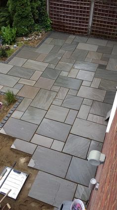 an outdoor patio is being built in the back yard, with tools and supplies on the ground