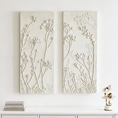 two white flowers are on the wall next to each other in front of a dresser