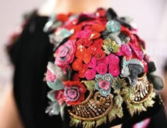 a close up of a woman's hand holding a bouquet of flowers and brooches