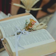 an open book sitting on top of a table next to a vase with flowers in it