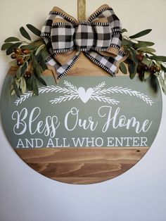 a wooden sign with a bow hanging from it's side that says, bless our home and all who enter