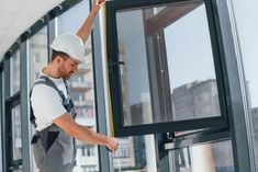 a man in overalls and a hard hat is opening the glass door