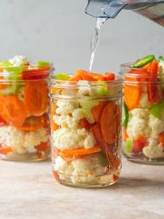 three jars filled with different types of vegetables