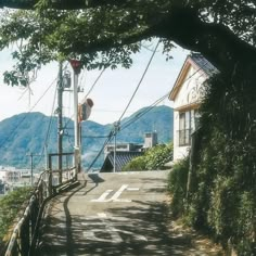 an empty road with power lines above it and mountains in the background