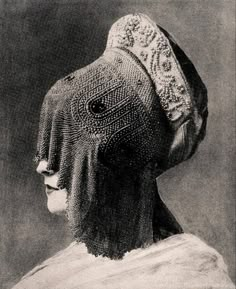 an old black and white photo of a woman's head wearing a knitted bonnet