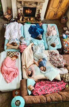 several people sleeping on mattresses in front of a fire place with blankets around them